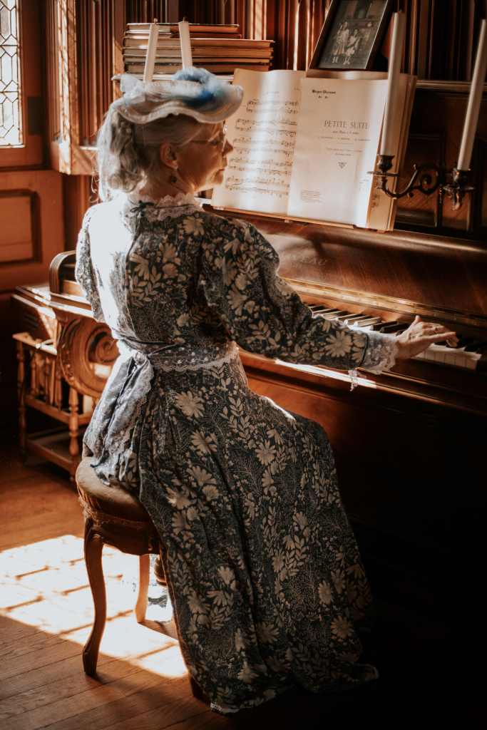 Femme en robe à tournure au château de Josselin dans le Morbihan, jouant du piano