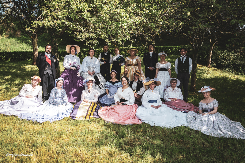 Participants en costumes historiques avec touches violettes dans un verger