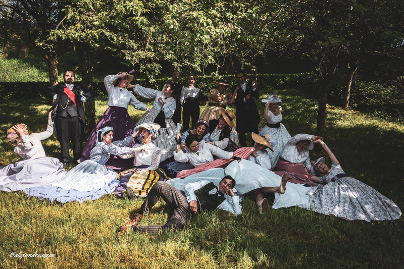Participants en costumes historiques avec touches violettes dans un verger
