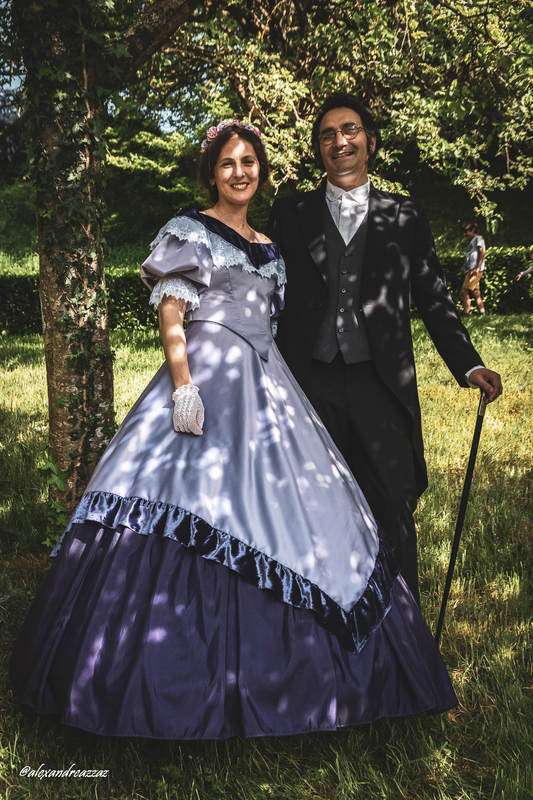 Participants en costumes historiques avec touches violettes dans un verger