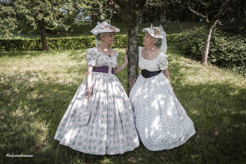 Participants en costumes historiques avec touches violettes dans un verger