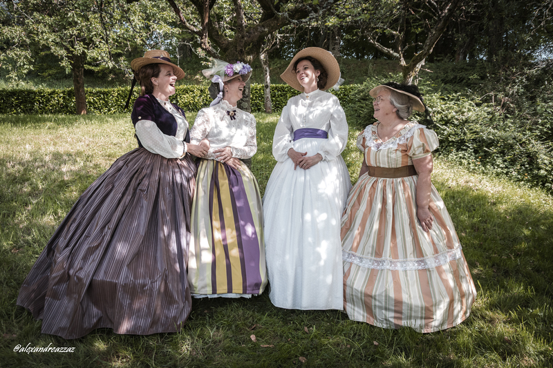 Participants en costumes historiques avec touches violettes dans un verger