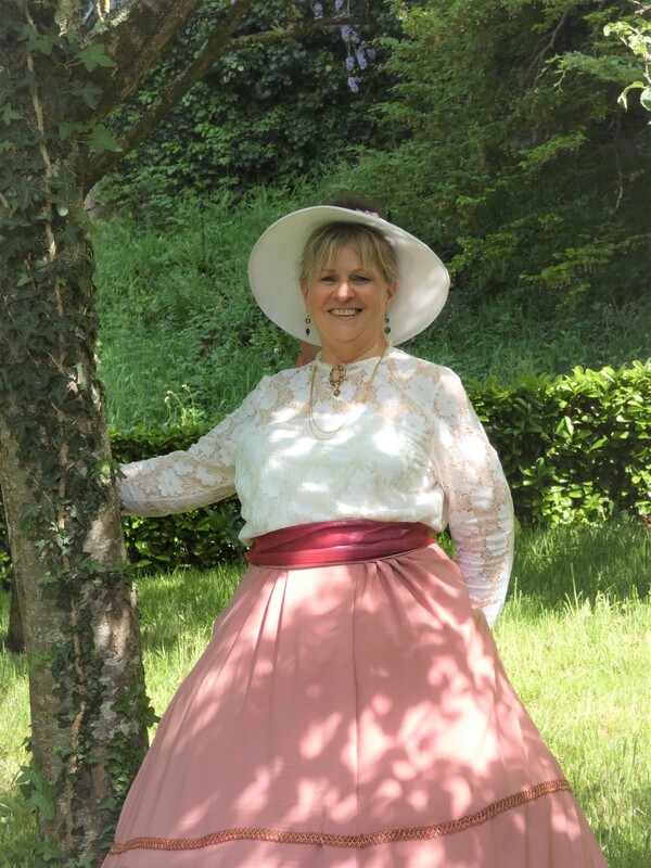 Participants en costumes historiques avec touches violettes dans un verger